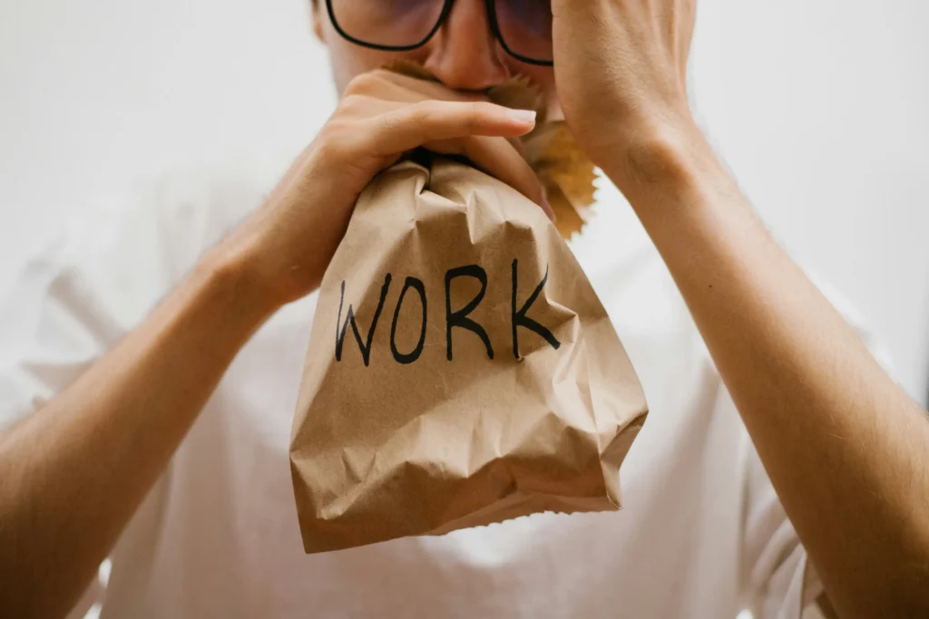 Man stressed and breathing into a bag that says work