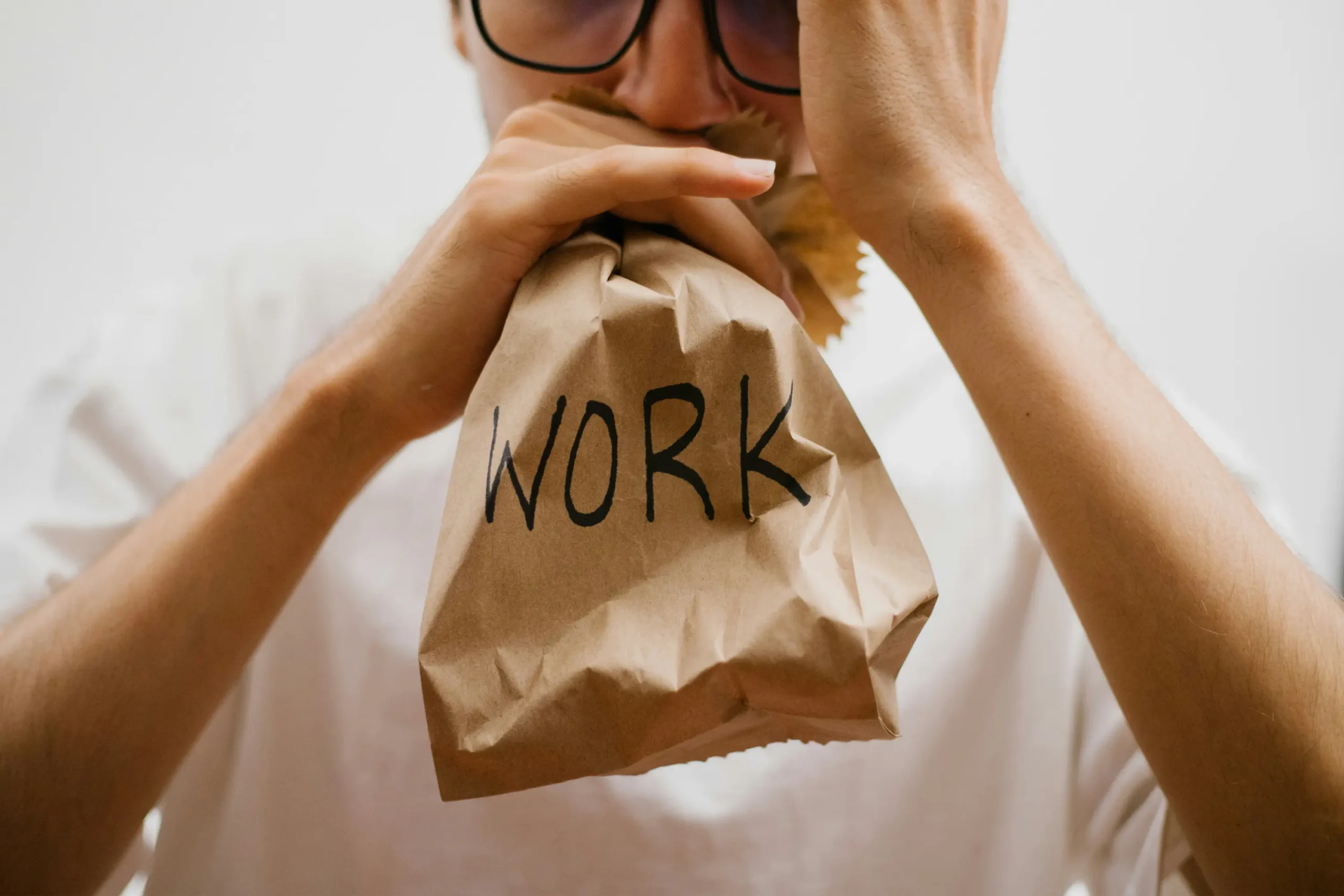 Man stressed and breathing into a bag that says work