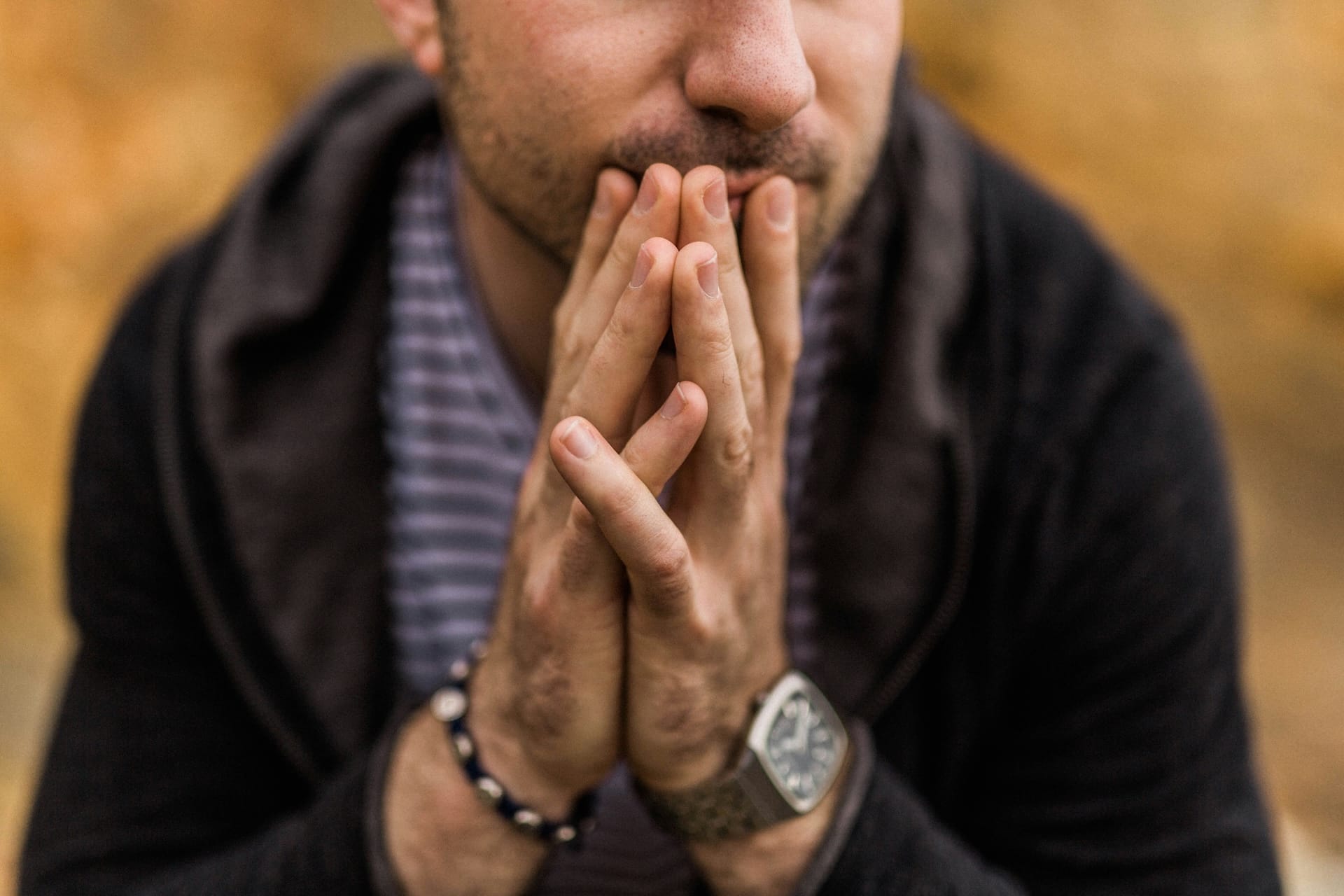 Man with his fingers together in front of his face, looking anxious