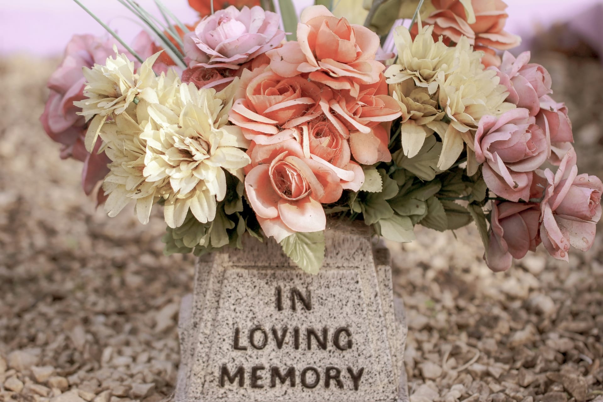 Flowers in a marble vase that says 'in loving memory'